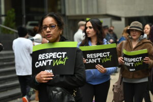 Three members hold signs during rally. 