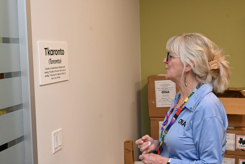 Woman looks at sign reading, “Tkaronto (Toronto).”