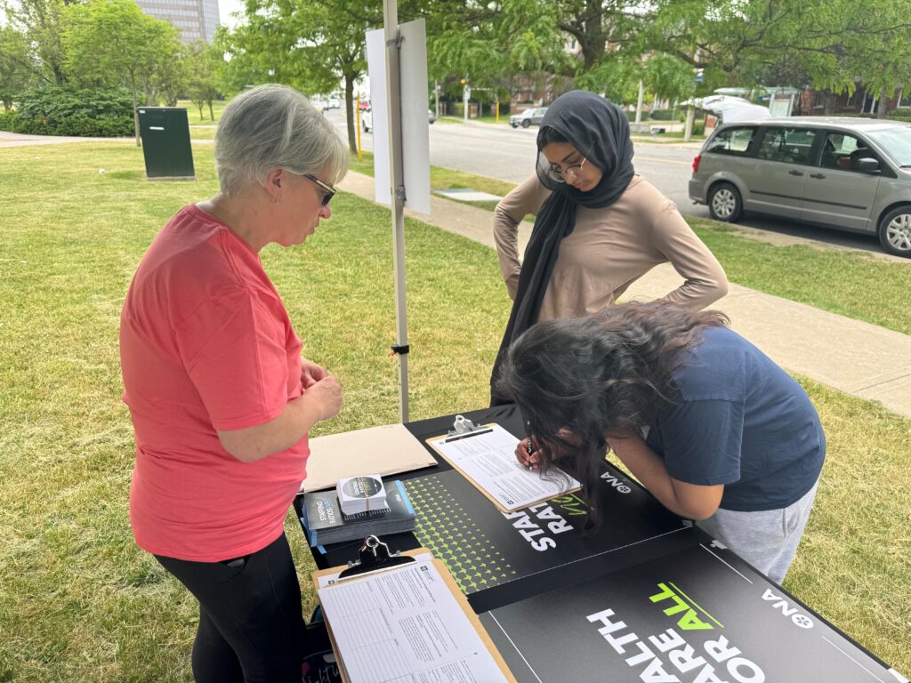 One woman signs a petition, while two others look on.