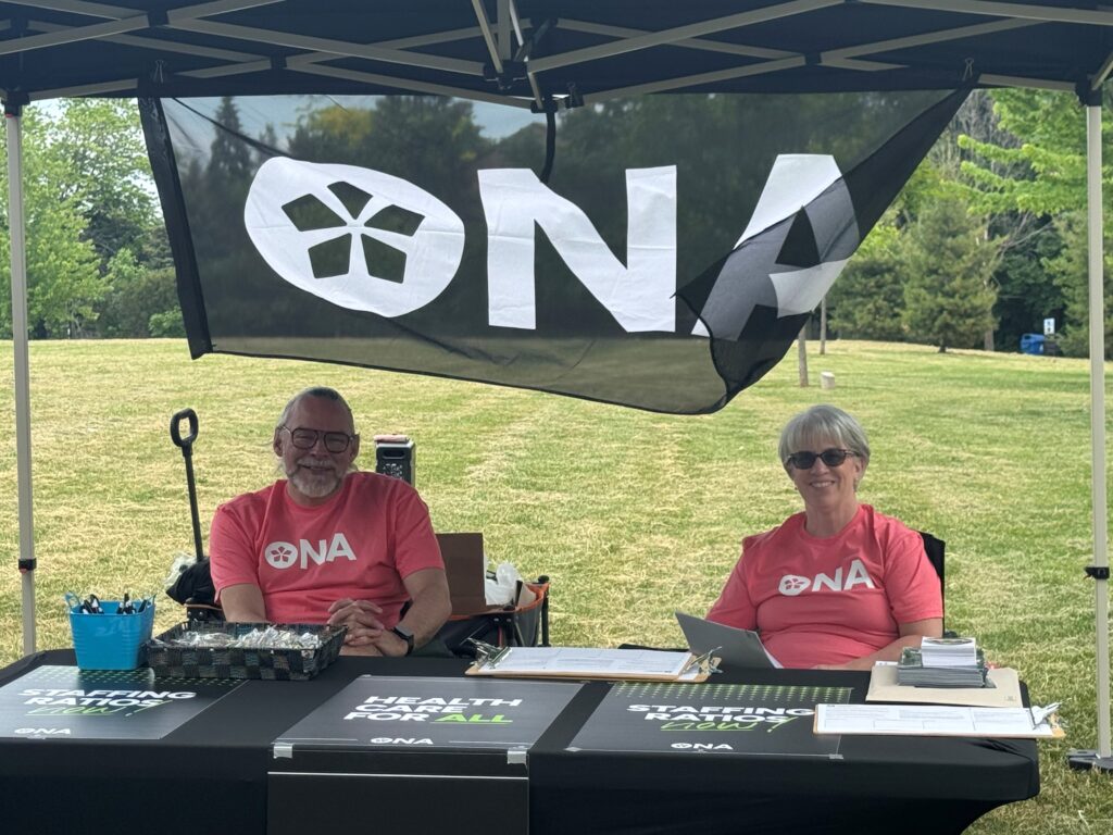 Man and woman sitting down at a table outside smile.