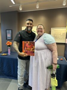 A man holding a book and a woman smile at the camera.