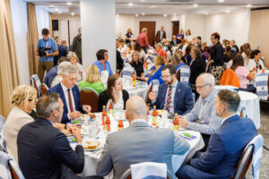 Shot of people sitting around tables in a large room.