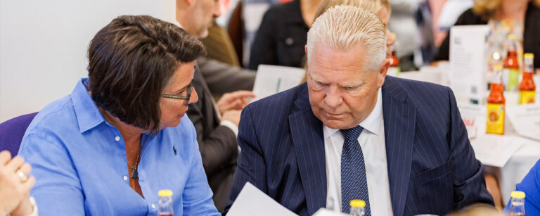 ONA Provincial President Erin Ariss and Premier Doug Ford talk to each other while sitting at a round table with others.