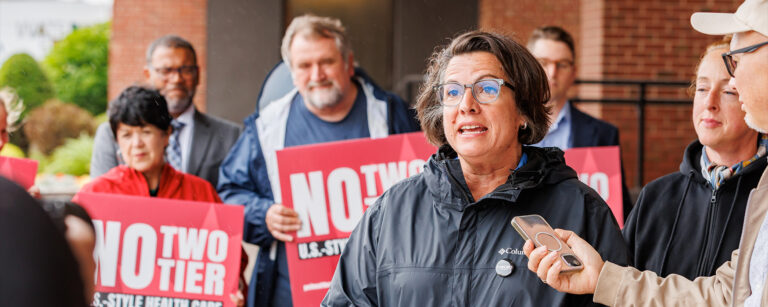 ONA Provincial President Erin Ariss is surrounded by others as she speaks from her notes.