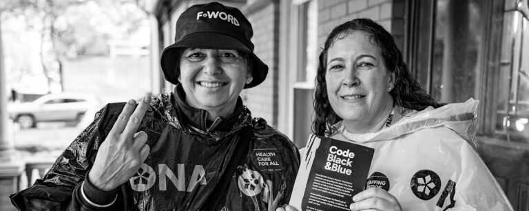 Members Ruby Panna and Karen McCoy jointly hold an ONA leaflet.