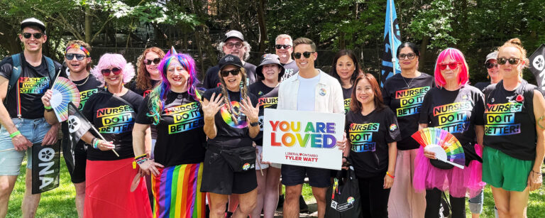 Group photo showing the ONA Pride contingent in colourful t-shirts with lots of embellishments.