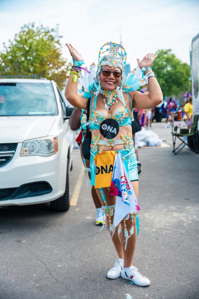 ONA member Gloria Cardinal-Tan stands on the street in her bright costume.