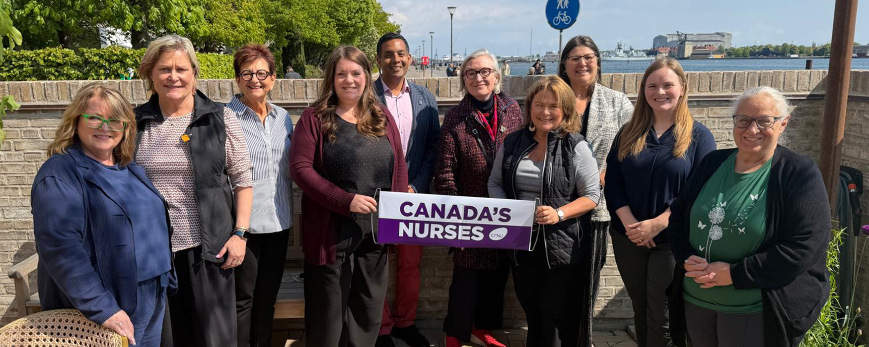 A group of 10, including ONA member Joann Carey, stand outside holding a sign reading, “Canada’s nurses.”