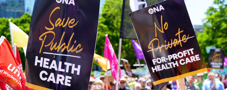Two ONA signs at a rally read, “Save Public Health Care” and “No Private For-Profit Health Care.”