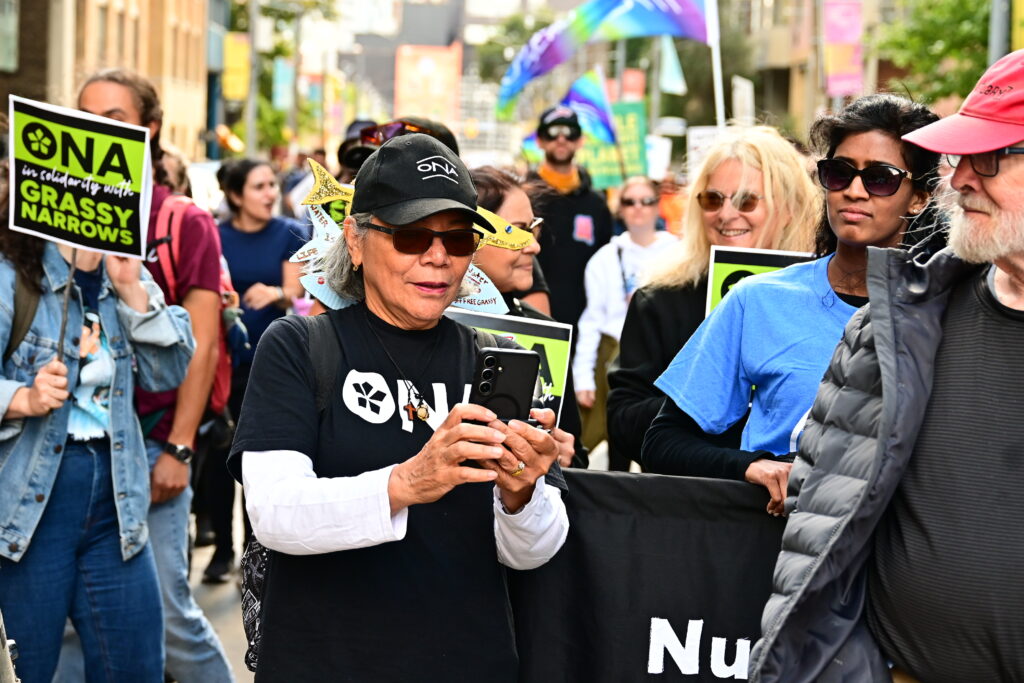An ONA member surrounded by many others holds her phone.