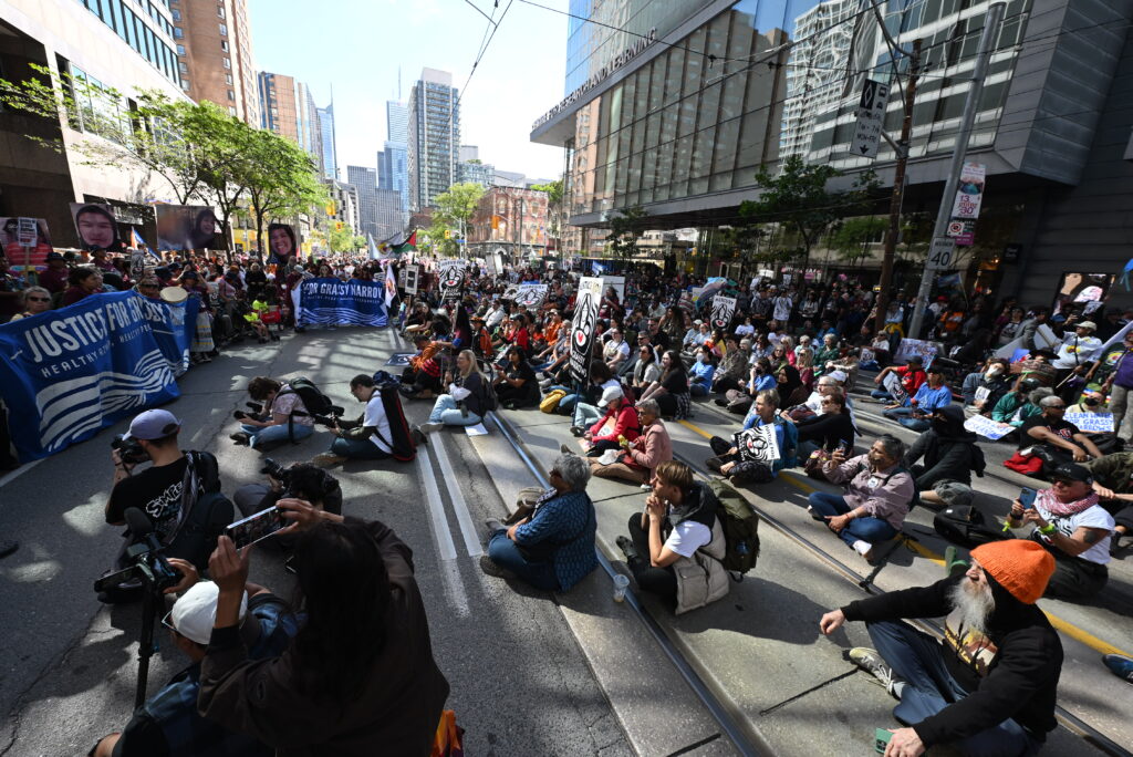 Several people sit on the street during a moment of silence.