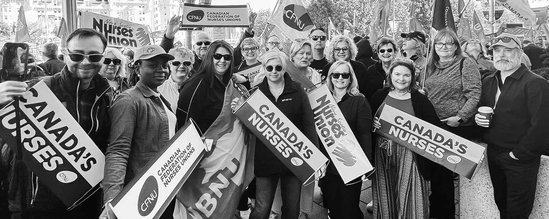 Representatives from the CFNU and provincial nursing unions hold their flags at a rally.